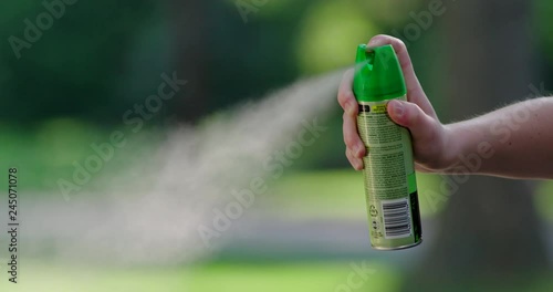 Medium shot of hand spraying mosquito insect repellent aerosol can in slow motion photo