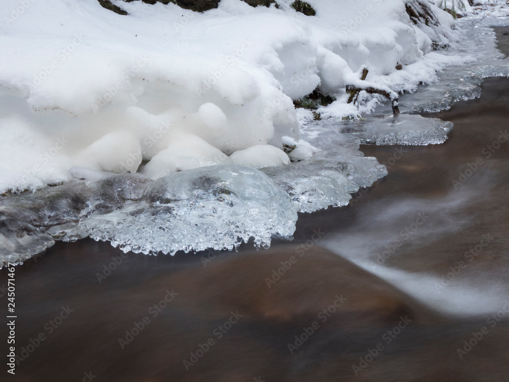 smooth motion of wild water in a river in winter with snow and ice on rocks and stones in the beautiful nature of a forest smooth motion of wild water in a river in winter with snow and ice on rocks and stones in the beautiful nature of a forest