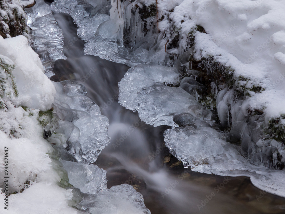smooth motion of wild water in a river in winter with snow and ice on rocks and stones in the beautiful nature of a forest smooth motion of wild water in a river in winter with snow and ice on rocks and stones in the beautiful nature of a forest