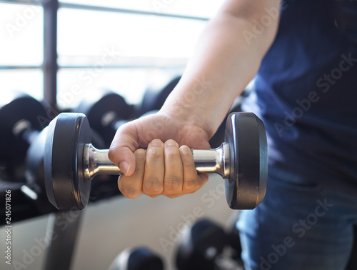 Women's arm is lifting a​ dumbbell for weight training​ in​ fitness center.