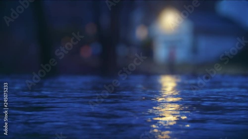 Rising flood waters encroach on the front steps of a nearby home at night