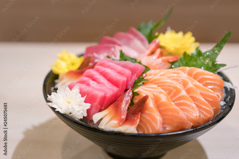 Mixed sliced fish sashimi on ice in black bowl. Sashimi Salmon Tuna Hamachi Prawn and Surf Calm set, raw fish, japanese food in Asian restaurant. Mixed sliced fish sashimi on ice in black bowl. Sashimi Salmon Tuna Hamachi Prawn and Surf Calm set, raw fish, japanese food in Asian restaurant.