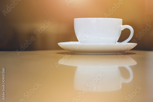 closeup white coffee cup with reflection on wooden table