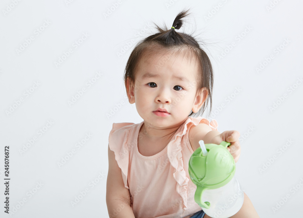 Cute Asian girl drinking milk with a bottle. On white background Cute Asian girl drinking milk with a bottle. On white background