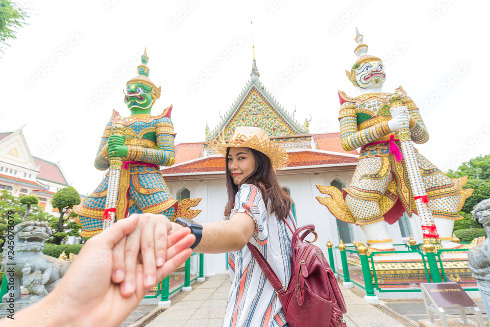 Obraz premium Tourist asian women leading boyfriend hand to travel in buddha temple of dawn