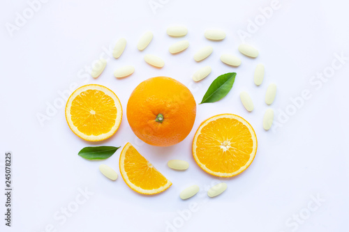 Vitamin C pills with orange fruit on white.