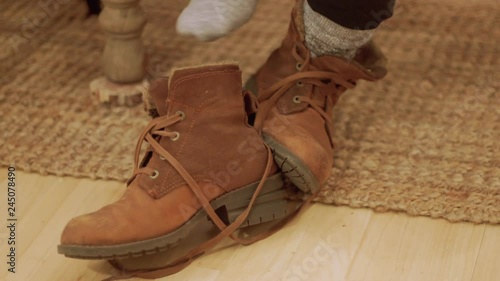 Young woman uses her feet to take off boots coming inside on very cold day