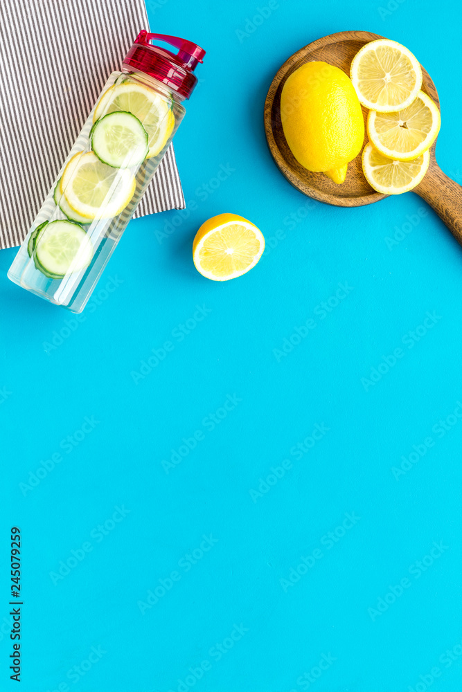 Make detox fruit water. Slices of lemon and cucumber in bottle on blue background top view copy space