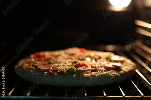 Pizza with ham and cheese in the electric oven.