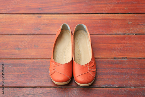 Orange leather female shoes on wood