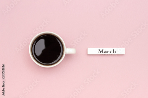 Wooden calendar spring month March and Cup of black coffee on pastel pink paper background. Concept Hello March Creative Top view Flat Lay Greeting card