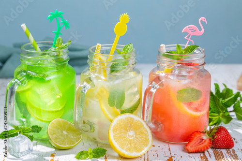 Selection of summer lemonades in glass jars, harsh sun light, copy space