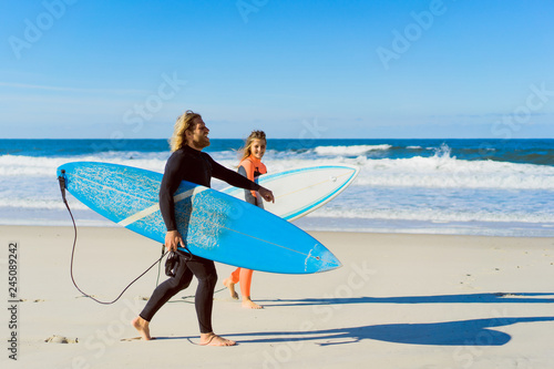 man and woman go to the ocean with surf boards. man and girl go surfing, Portugal, Nazaré. Surfing in a wet suit.