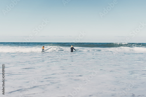 man and woman go to the ocean with surf boards. man and girl go surfing, Portugal, Nazaré. Surfing in a wet suit.