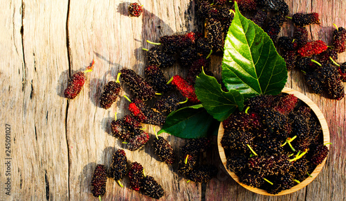 Close up of Mulberries organic fruits in wooden bowl on wood backgrounds above