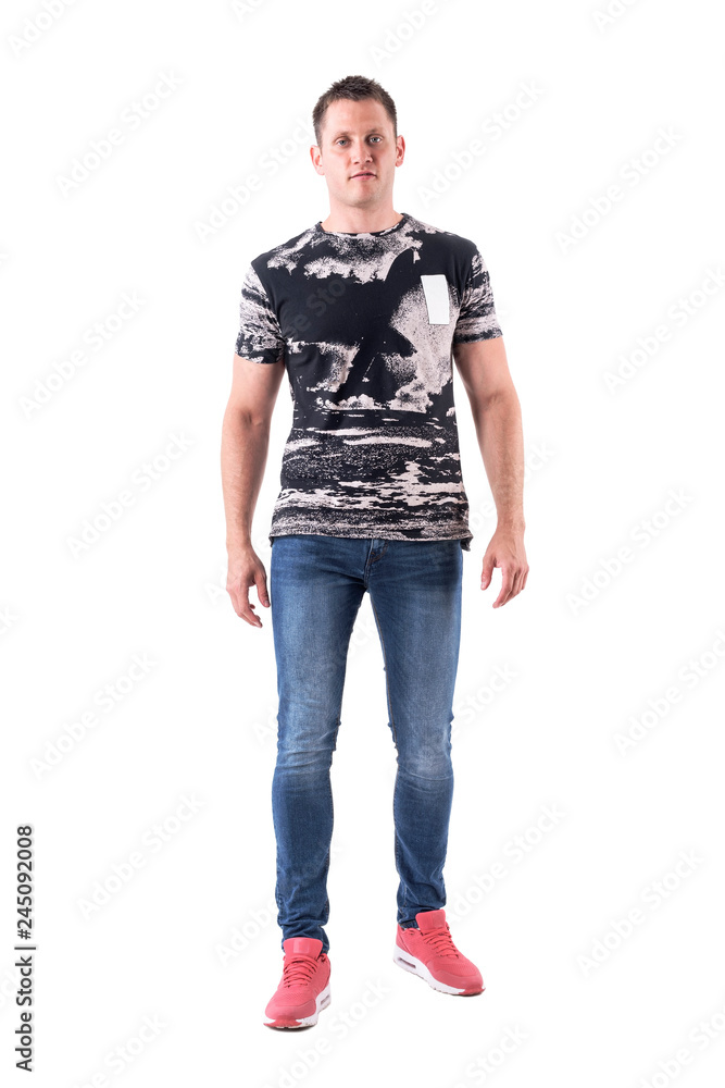 Confident serious young adult man looking at camera with arms down. Full body isolated on white background. Confident serious young adult man looking at camera with arms down. Full body isolated on white background.