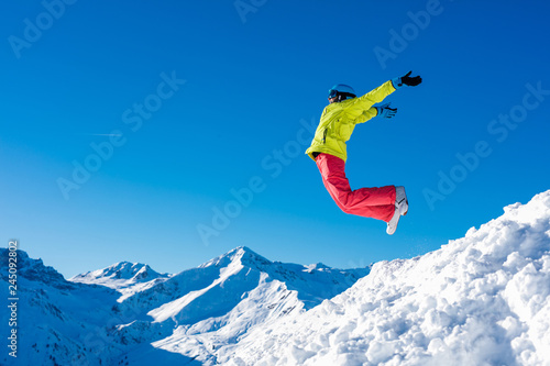 Girl snowboarder jumping and having fun in the winter ski resort.
