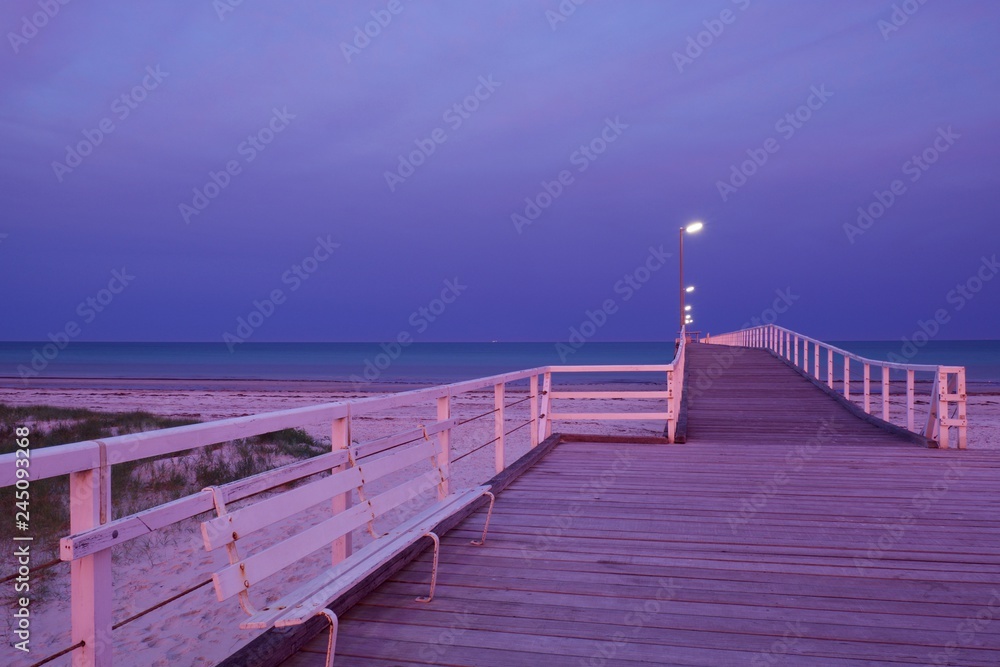 Photo of a jetty or pier with orange pink backlighting from a morning sunrise