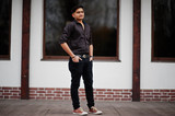 Indian man in brown shirt posed outdoor.