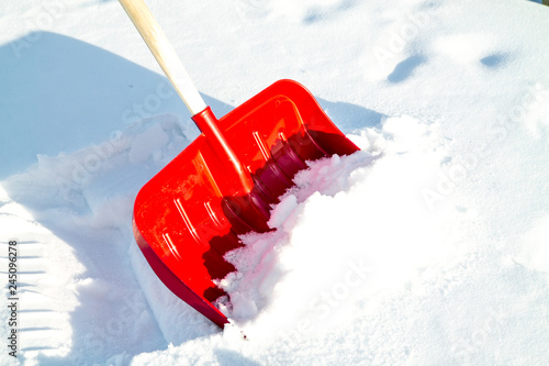 Close up of big red plastic showel in the process of removing the snow in winter