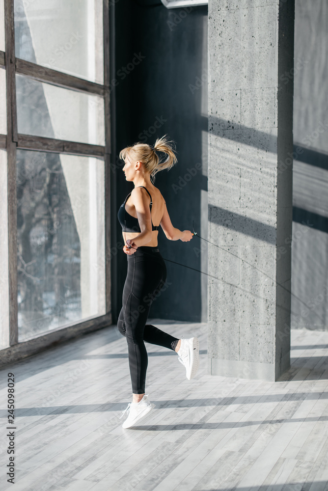 Beautiful woman jumping rope in fit stodio