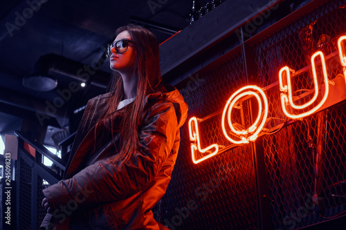 Young stylish girl wearing a hoodie coat and sunglasses standing on stairs at...