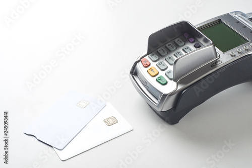 Credit cards and payment terminal on white table background.