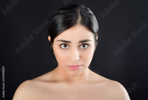 Beauty Portrait of young brunette girl with bare shoulders on black background
