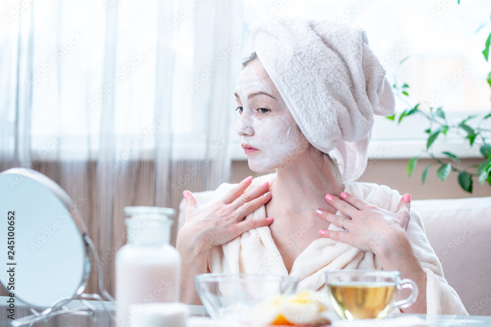 Beautiful happy woman with cosmetic natural mask on her face looking at her skin. Skin care and Spa treatments at home Beautiful happy woman with cosmetic natural mask on her face looking at her skin. Skin care and Spa treatments at home