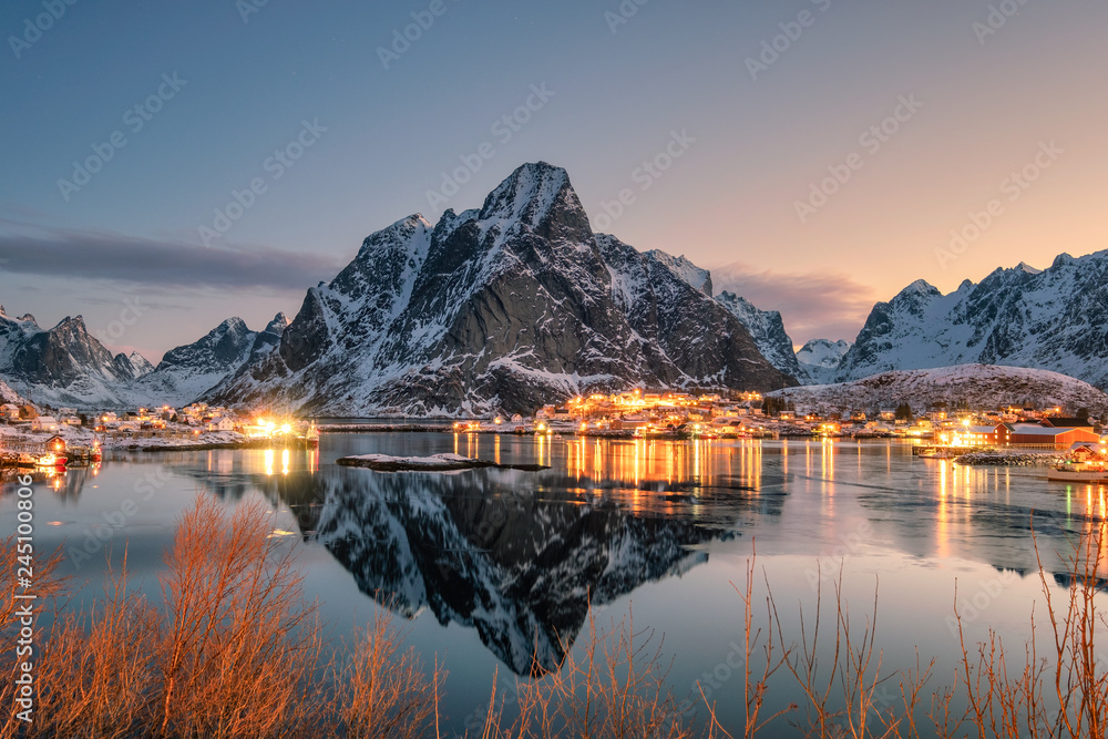Fishing village illumination with mountain range  reflection on coastline at dawn