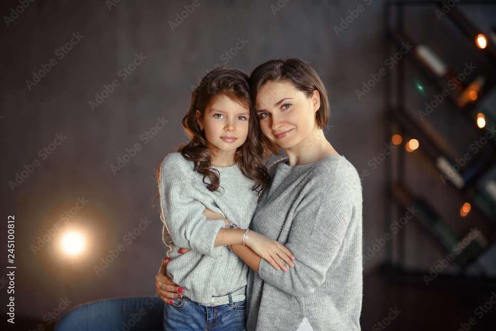 Young mother and her daughter at dark interior.