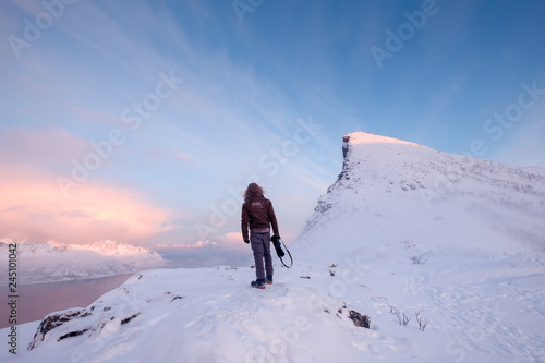 Tourist man climbs on top snowy mountain