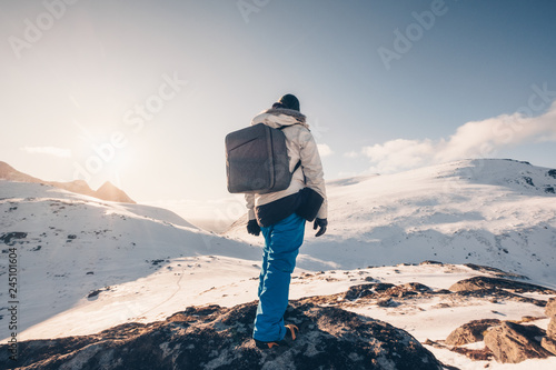 Rear backpacker standing on rock in snowy valley