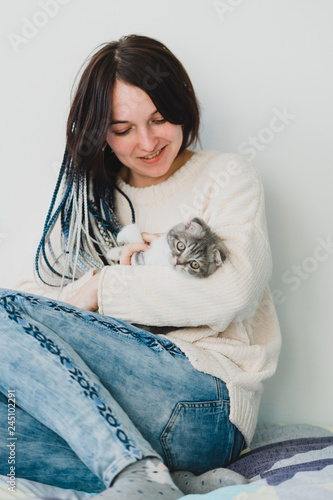 Pretty little kitten in hands looking at the owner in the cozy bedroom 