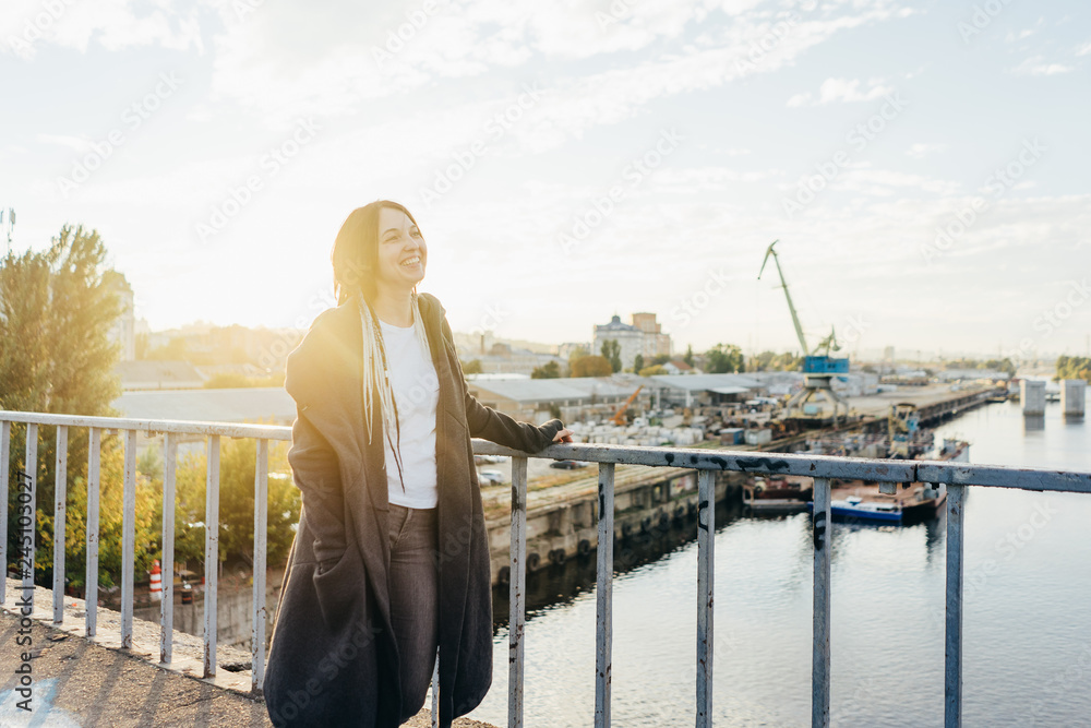 Happy smiling young woman in the city at the sunset