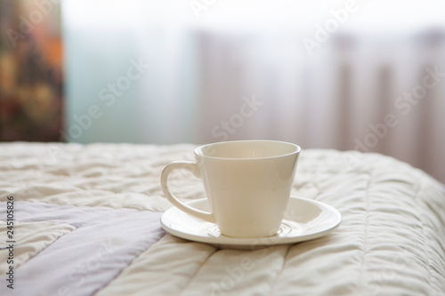 Morning cup of coffee on the background of the bed and the window