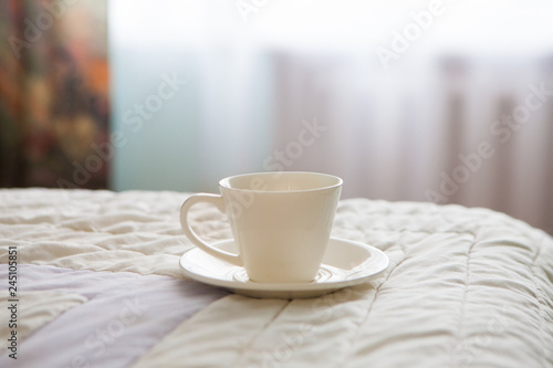 Fototapeta Naklejka Na Ścianę i Meble -  Morning cup of coffee on the background of the bed and the window