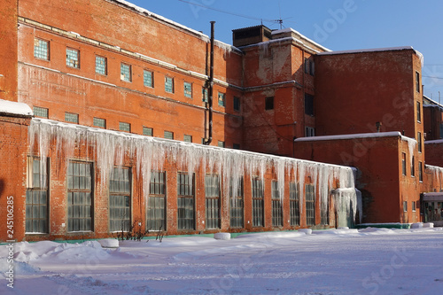 The old factory of the Soviet period of red brick in the winter. Big icicles on the roof. Winter. The Moscow Region. Russia