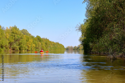 Couple (man and woman) paddle a yellow kayak at Danube river. Spring kayaking and water tourism and recreational © watcherfox