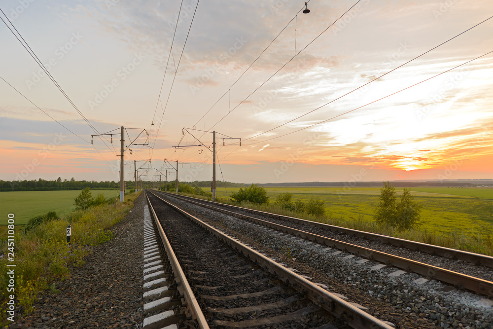 empty railroad with pillars in the open field at sunset