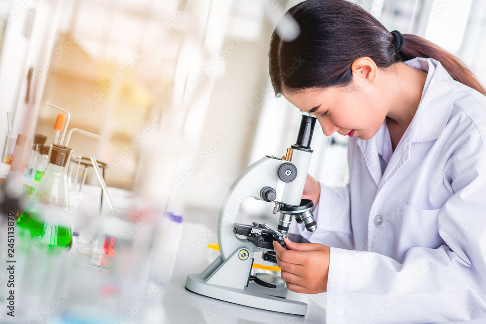 Scientist sing microscope in laboratory with lab glassware containing chemical liquid, science or medical research and development concept Scientist sing microscope in laboratory with lab glassware containing chemical liquid, science or medical research and development concept