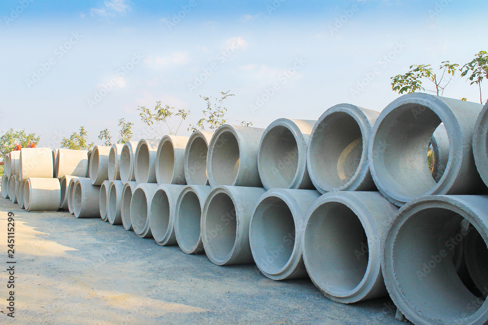 Big stacks of concrete sewage pipes on the ground prepare for underground instalation and blue sky background Big stacks of concrete sewage pipes on the ground prepare for underground instalation and blue sky background