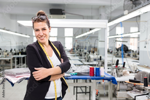 Adult woman designer posing with arms crossed in factory.