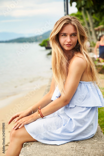 Pretty girl at beach, sitting on wall