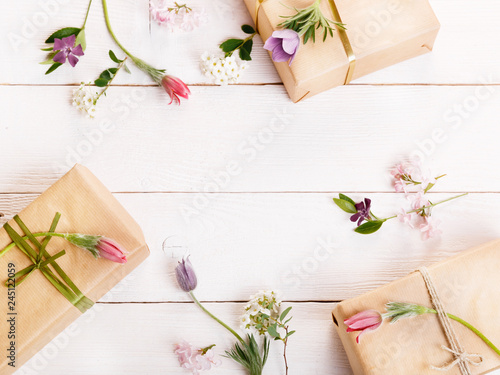 Flowers composition. Workspace with spring flowers, gift, paper bag. Top view, flat lay.