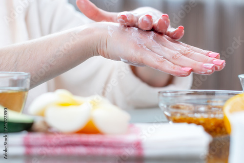 Woman applying the cream on her hands nourishing them with natural cosmetics close-up. Hygiene and care for the skin