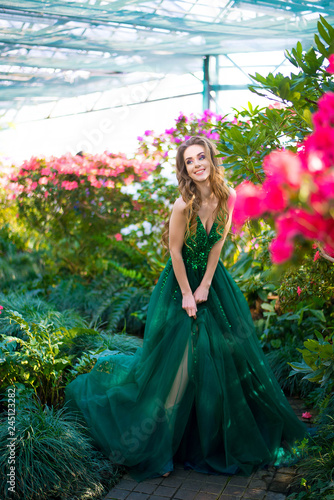Beautiful woman with blue eyes in a green dress near azalea flowers © hohmochka