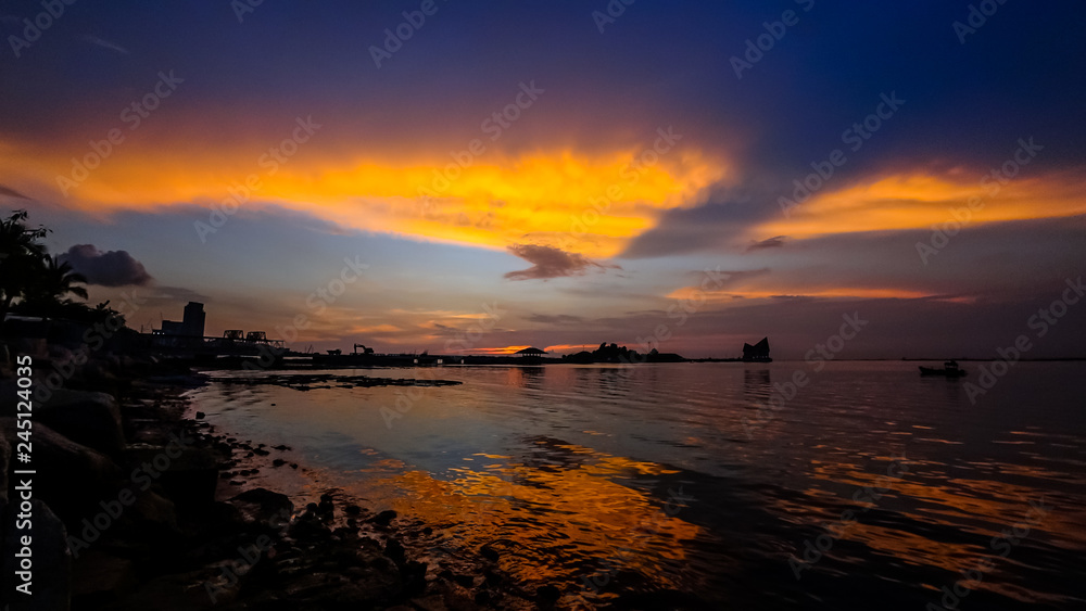 Dramatic sunset sky at sea with silhouette of island background
