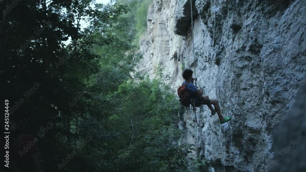 male climber down the rope along the cliff male climber down the rope along the cliff