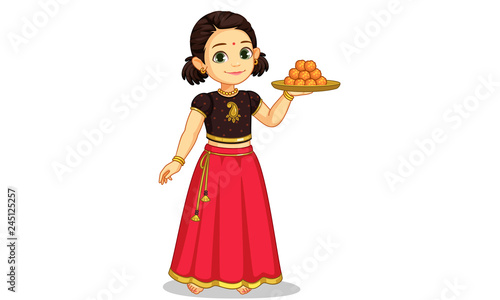 Cute little girl in traditional wear holding a plate of sweets